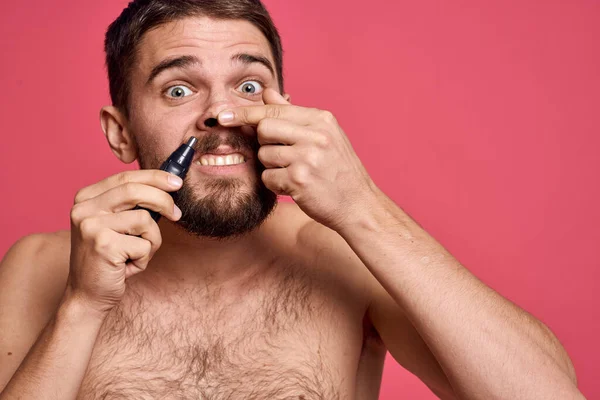 Skäggig man bara axlar tar bort hår från näsan kroppsvård rosa bakgrund — Stockfoto