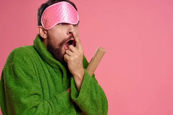 Egy férfi rózsaszín álarcmaszkkal az arcán zöld köntösben, sodrófával a kezében. — Stock Fotó