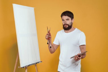 Erkek sanatçı palet resim sehpası hobi yaşam tarzı yaratıcılık sarı arka plan