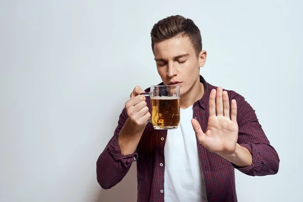 Fylld man med en mugg öl semester alkohol livsstil i en röd skjorta känslor ljus bakgrund — Stockfoto