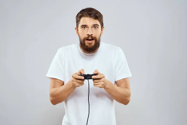 Un hombre con un mando en sus manos jugando juegos ocio estilo de vida tecnología blanco camiseta fondo claro —  Fotos de Stock