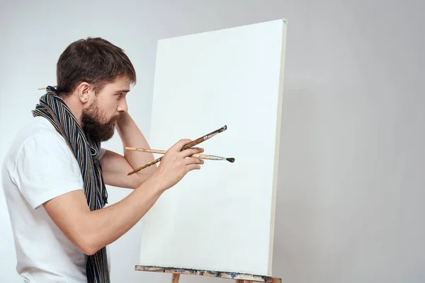 Male artist brush in hands of easel art hobby light background scarf around his neck