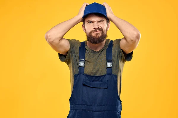 Worker man in uniform worker service yellow background emotion — Stock Photo, Image
