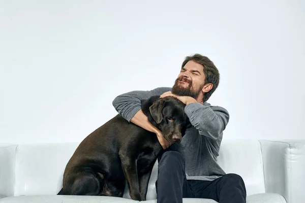 Hombre con un perro mascota en el sofá divertido amigos emociones sala de luz — Foto de Stock