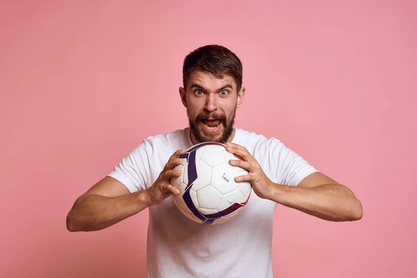 Чоловік з футбольним м'ячем на рожевому фоні енергія жестикулювати своїми руками тренер емоційної моделі — стокове фото