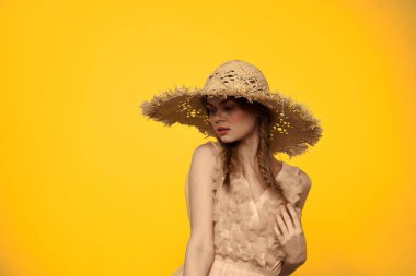 Sarı arkaplan duygularıyla elinde hasır şapkalı bir kadın... 