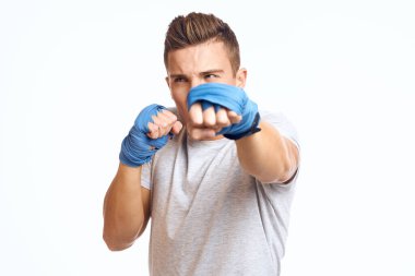 Mavi eldivenli sporcu erkek boksör arka planda hafif kesikli bir manzarada yumruk çalışıyor.