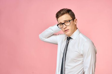 Beyaz gömlekli, kravatlı, gözlüklü, kendine güvenen, resmi pembe arka planlı bir iş adamı.