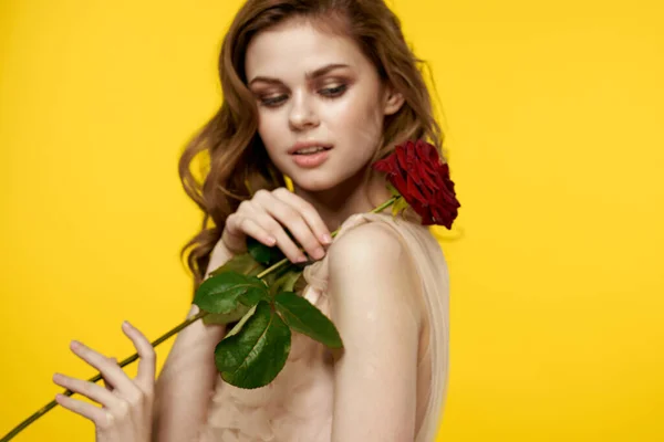 Romantyczna dziewczyna na żółtym tle z czerwonym kwiatem w dłoni i modelem sukni wieczorowej — Zdjęcie stockowe