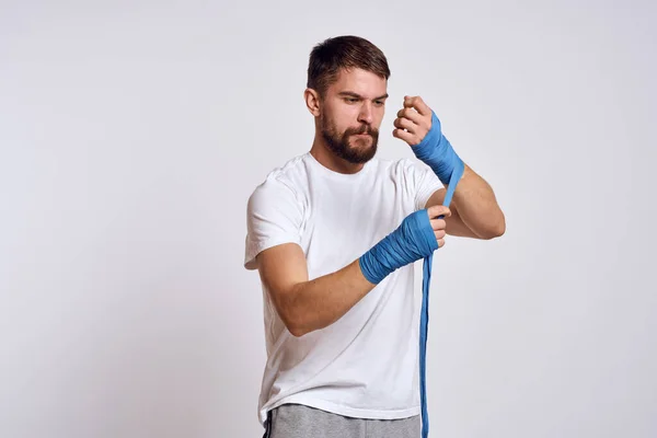 Homem de esportes em branco t-shirt azul bandagens de boxe em seus exercícios de treino de braços — Fotografia de Stock