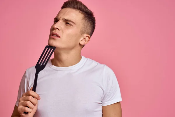 Homme avec des outils de cuisine sur fond rose spatule pour la cuisson modèle vue recadrée — Photo