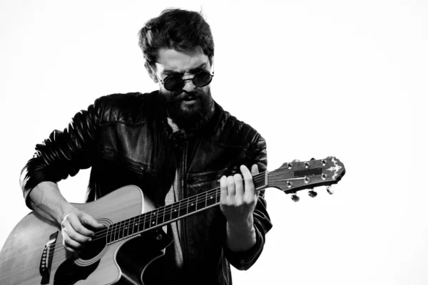 A man holds a guitar in his hands music emotions black leather jacket dark glasses studio light background