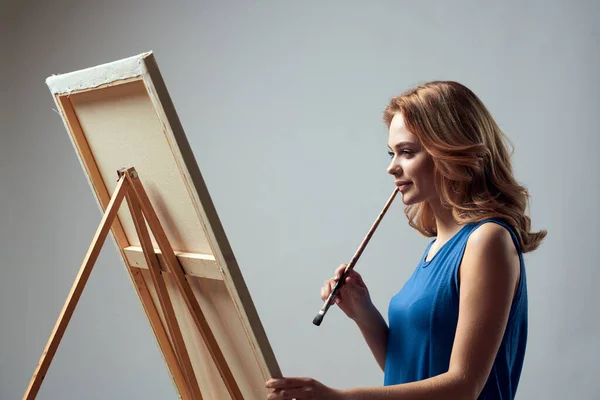 Mulher artista com pintura escova no cavalete arte hobby luz fundo — Fotografia de Stock