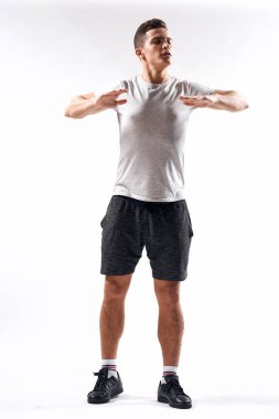 Şortlu bir sporcu ve arka planda hafif jestler yapan tişörtlü bir adam.