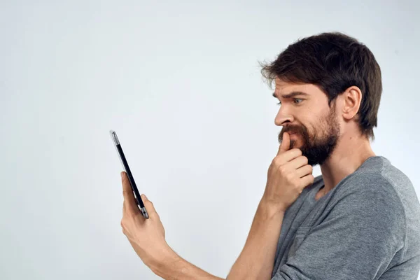 Ein Mann mit einem Tablet in der Hand Internet-Technologie Kommunikation graue Jacke heller Hintergrund — Stockfoto