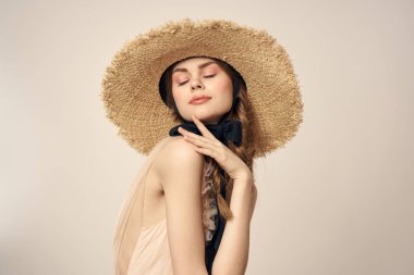 Bej elbiseli, hasır şapkalı, siyah kurdele takmış, manken görünümlü romantik bir kız.