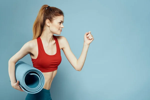 Esterilla de entrenamiento de mujer deportiva en las manos Red Tank Top ejercicio fondo azul —  Fotos de Stock