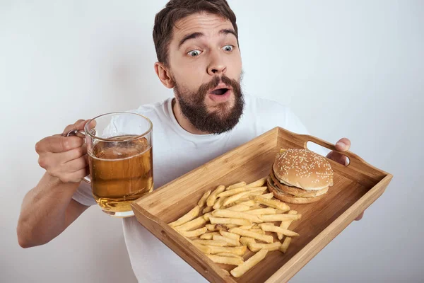 man with wooden tray beer mug french fries and hamburger fast food calories model white t-shirt
