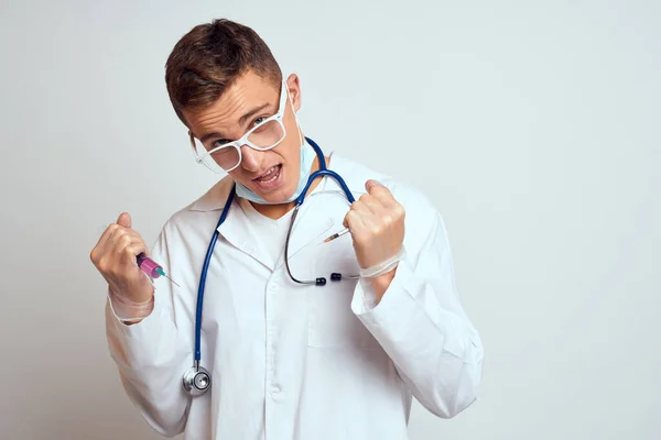Médico en un vestido médico con un estetoscopio y gafas sobre un fondo claro recortado ver retrato —  Fotos de Stock