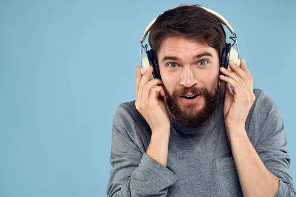 Homme avec casque dans les mains musique émotion technologie style de vie amusant fond bleu gros plan — Photo