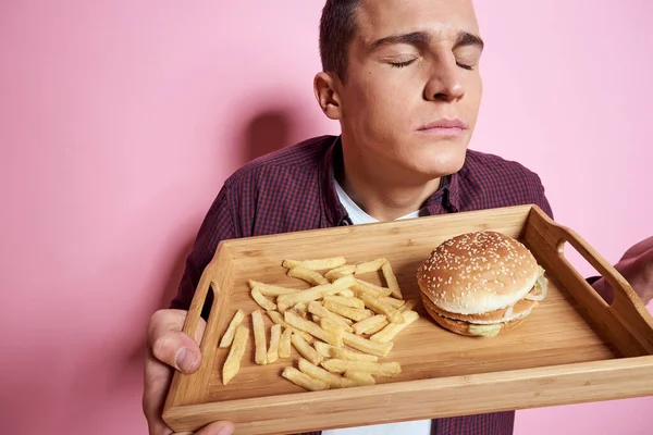 Hamburger yiyen bir adam patates kızartması yiyor. — Stok fotoğraf