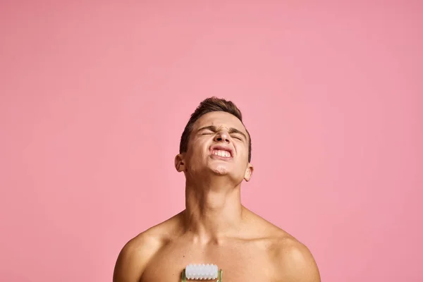 Hezký muž s masážním v ruce na izolovaném růžovém pozadí oříznutý pohled čistá kůže — Stock fotografie