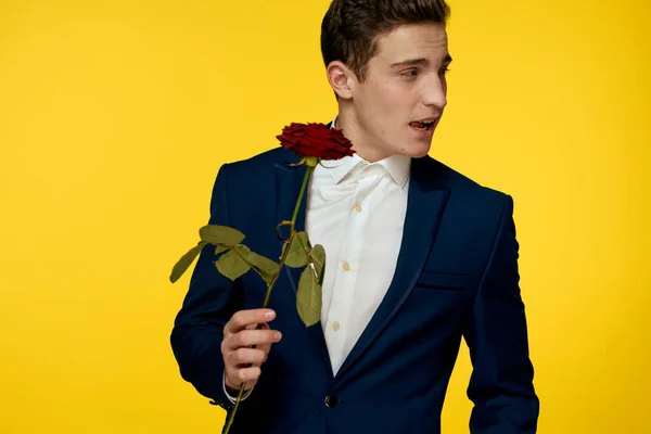Gentleman im klassischen Anzug auf gelbem Hintergrund mit roter Rosenromantik — Stockfoto