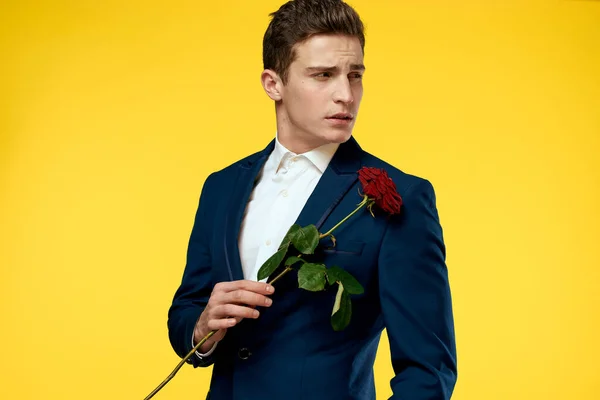 Herren im klassischen Anzug auf gelbem Hintergrund und roter Rose Romantik ausgeschnitten Ansicht Modell Porträt. — Stockfoto