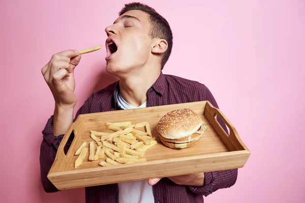 Mann mit Fast Food essen Hamburger Pommes rosa Hintergrund — Stockfoto