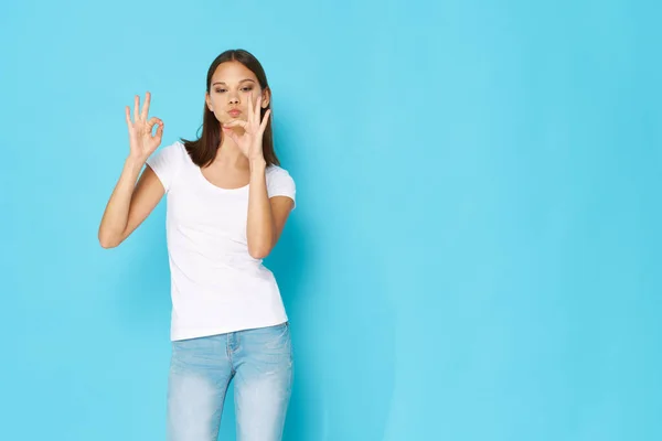 La ragazza nativa su uno sfondo blu sta gesticolando con le mani — Foto Stock