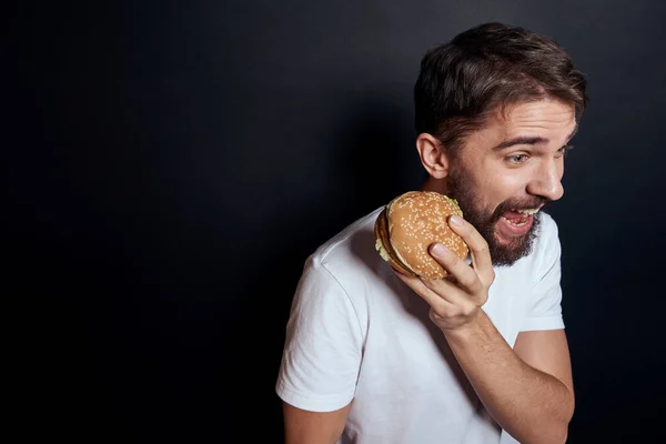 햄버거 패스트푸드 식당에서 식사하고 있는 남자 고르 메트는 어두운 배경을 먹고 있다 — 스톡 사진