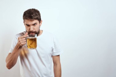 Elinde bir kupa bira ve beyaz tişörtlü açık renk bıyıklı sakallı bir adam.