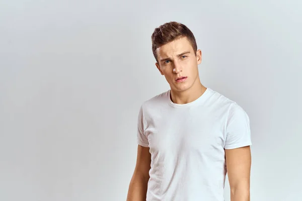 Hombre guapo en una camiseta blanca sobre un fondo claro retrato de cerca vista recortada —  Fotos de Stock