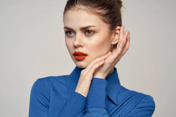 Portrait of a beautiful woman with red lips on a light background and a blue shirt cropped view — Stock Photo, Image