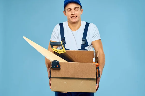 Pracovní muž v uniformě box s nářadí nakladač dodání modré pozadí — Stock fotografie