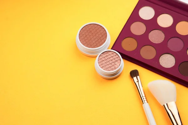 eyeshadow powder blush makeup brushes yellow background Copy space