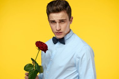 Gömlekli ve papyonlu bir beyefendi boynunda sarı arka planda kırmızı gül