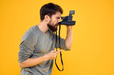 Profesyonel fotoğraf makinesi olan bir erkek fotoğrafçı. Profesyonel Yaratıcı yaklaşım stüdyo sarı arka plan