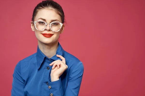 Retrato de una mujer en gafas y en una camisa azul labios rojos fondo rosa modelo — Foto de Stock