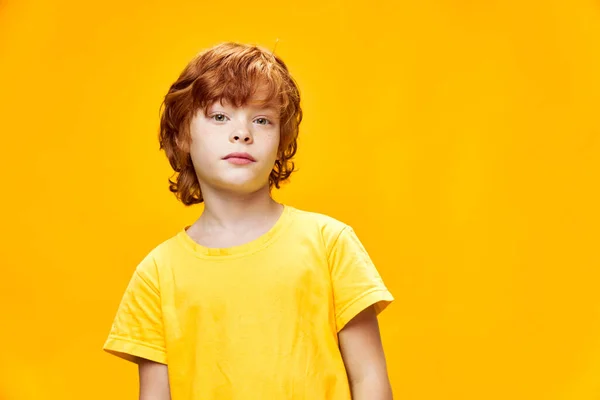 Rousse garçon en t-shirt jaune sur fond isolé regarde vers l'avant — Photo