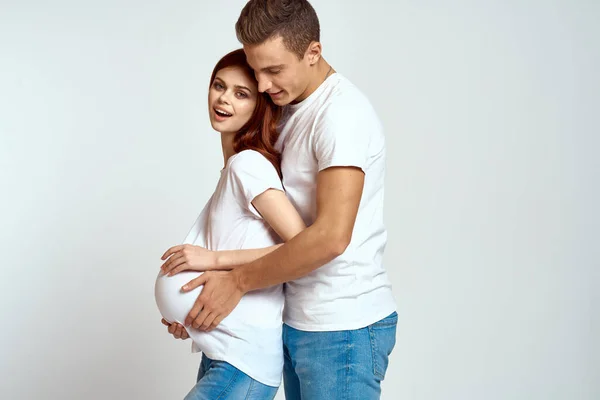 Беременная женщина и молодой человек ждут ребенка на легком фоне эмоций семьи любовь — стоковое фото