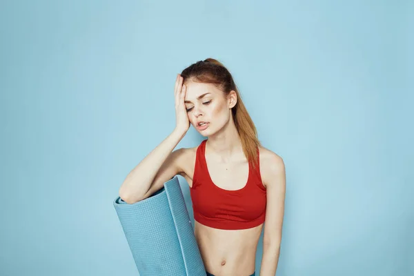Donna sportiva in rosso serbatoio top mat per esercizi di allenamento stile di vita sfondo blu — Foto Stock
