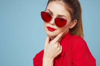 Gözlüklü ve kırmızı dudaklı bir kadının portresi. Mavi arka plan modeli.