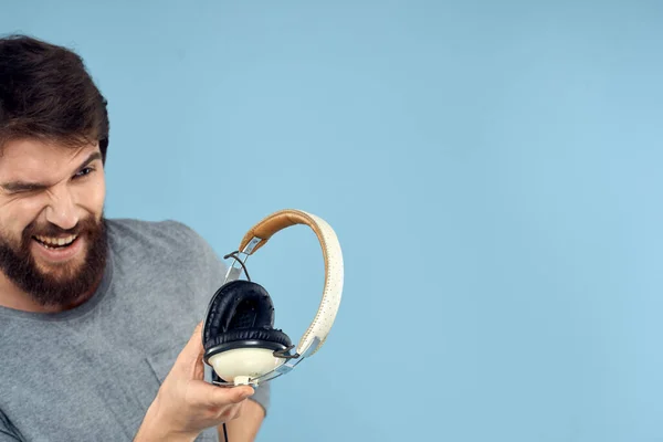 Man met hoofdtelefoon in handen muziek emotie technologie levensstijl plezier blauw achtergrond close-up — Stockfoto
