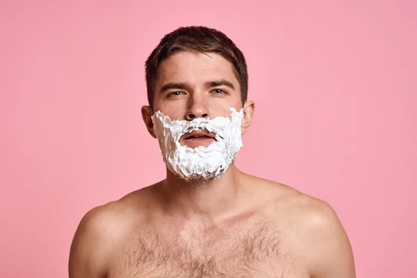 Man met scheermes en wit schuim op zijn gezicht roze achtergrond naakt romp baden behandelingen — Stockfoto