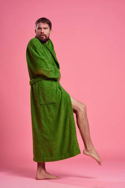 Эмоциональный человек в зеленом халате в полном разгаре на розовом фоне жестикулирует руками к модели — стоковое фото