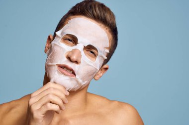 Mavi arka planda beyaz besleyici maskeli çıplak bir adam.