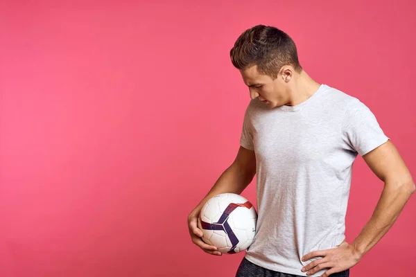 Uomo sportivo con pallone da calcio su sfondo rosa primo piano vista ritagliata — Foto Stock