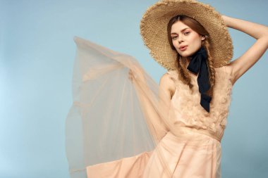 Mavi arka planda pembe elbiseli bir kız elleriyle romantik modeller yapıyor.