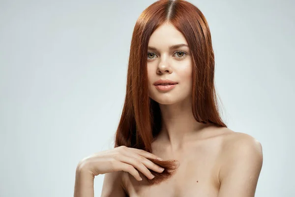 빨간 머리 여자가 수염을 기르고 있습니다. 손으로 털을 손질하고 있고 밝은 어깨 배경을 가지고 있죠. — 스톡 사진